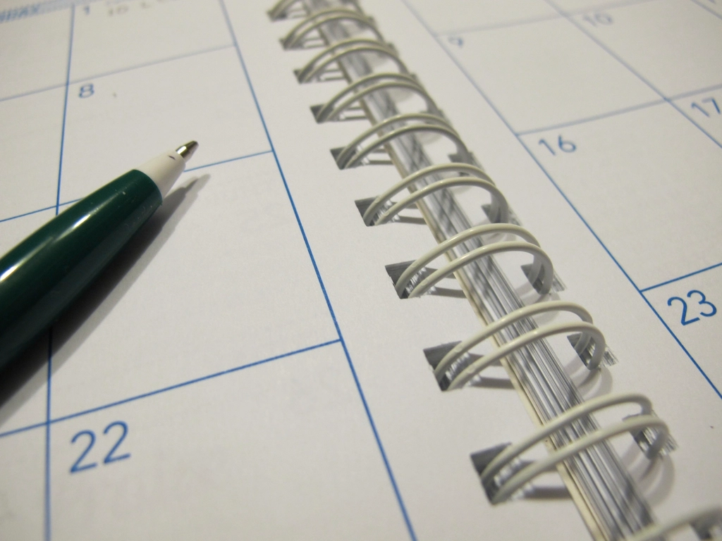 Abstract navy and gold toned photo of a desk calendar and pen, representing the weekly pace of model releases