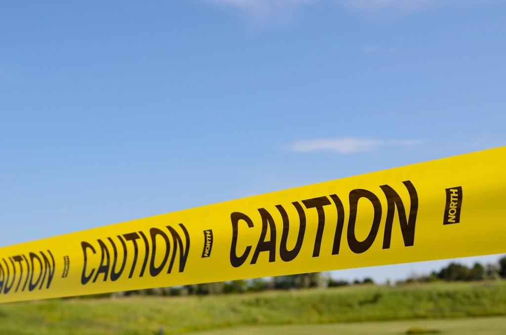 Abstract navy and gold toned photo of yellow caution tape, representing a safety report on autonomous coding agents
