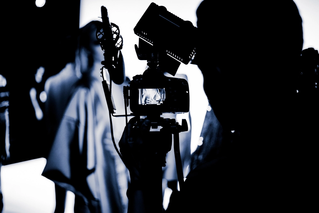 Abstract navy and gold toned photo of a video camera operator in silhouette, representing HeyGen multilingual video production