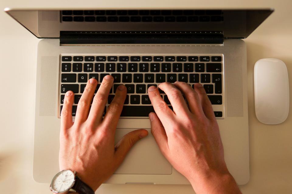 Overhead photo of hands typing on a laptop keyboard, representing AI-authored code at Anthropic