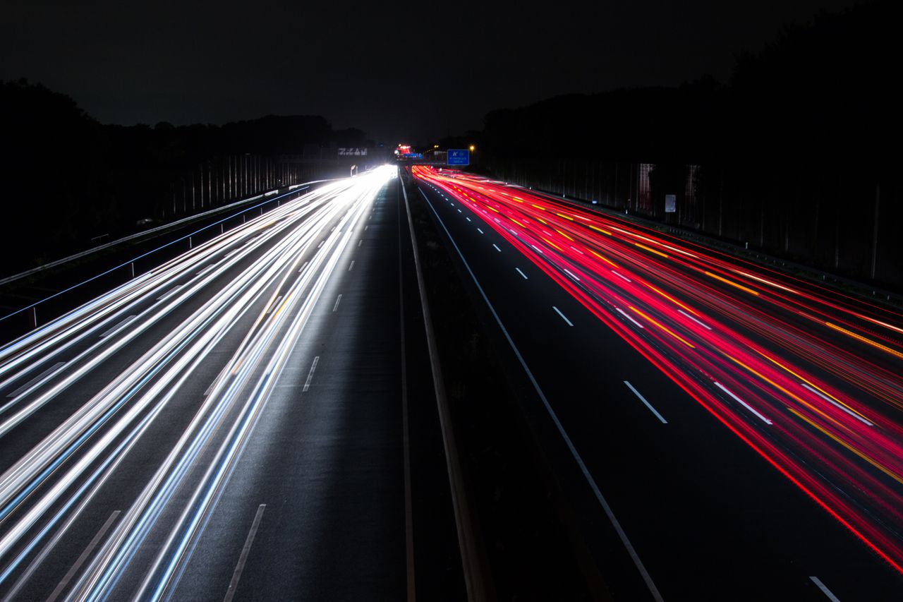 Navy and gold toned photo of light trails on a highway at night, representing a fast low-cost AI model