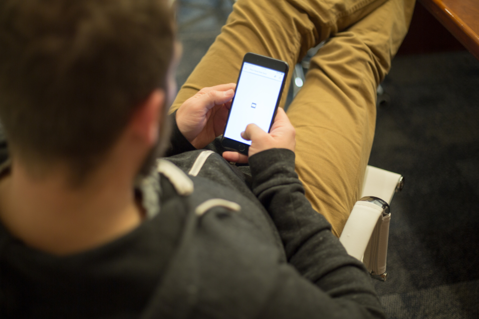 Navy and gold toned photo of a person using a smartphone, representing changes to free Gemini model access