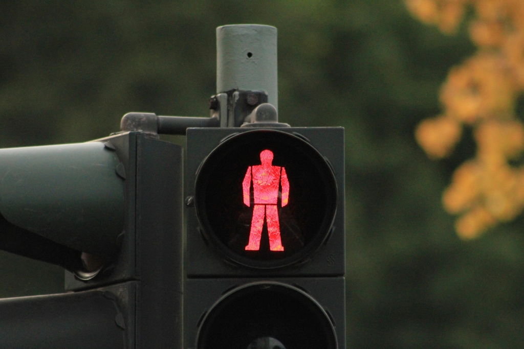 Navy and gold toned photo of a red pedestrian traffic light, representing OpenAI halting the GPT-6.1 Astra release