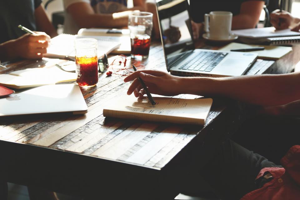 Navy and gold toned photo of a team working around a table with laptops, representing OpenAI Dots agents in team tools