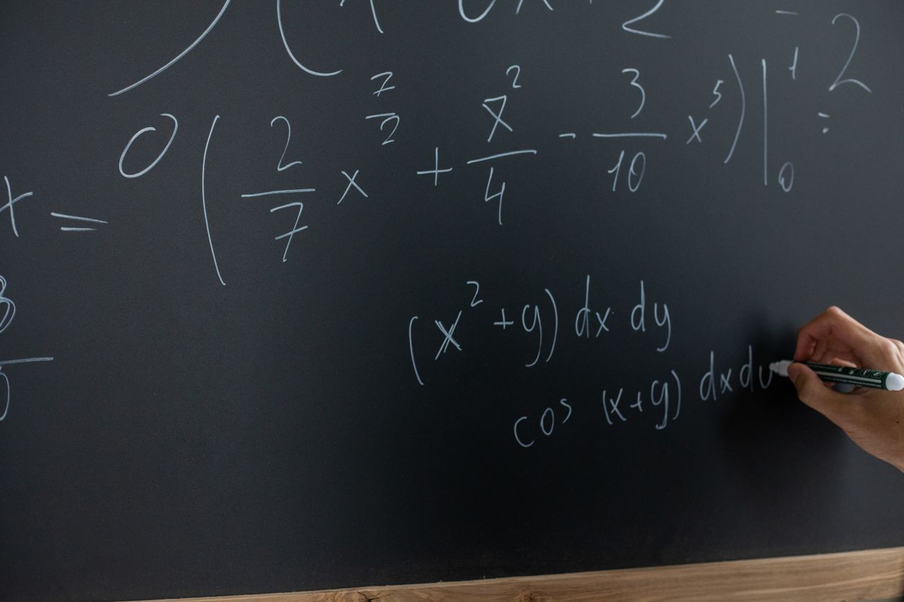 Navy and gold toned photo of equations written on a chalkboard, representing AI-generated math research